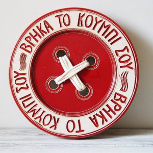 Red button wall sculpture, earthenware clay, scarlet button wall hanging with 'Found Your Button' inscription" in Greek