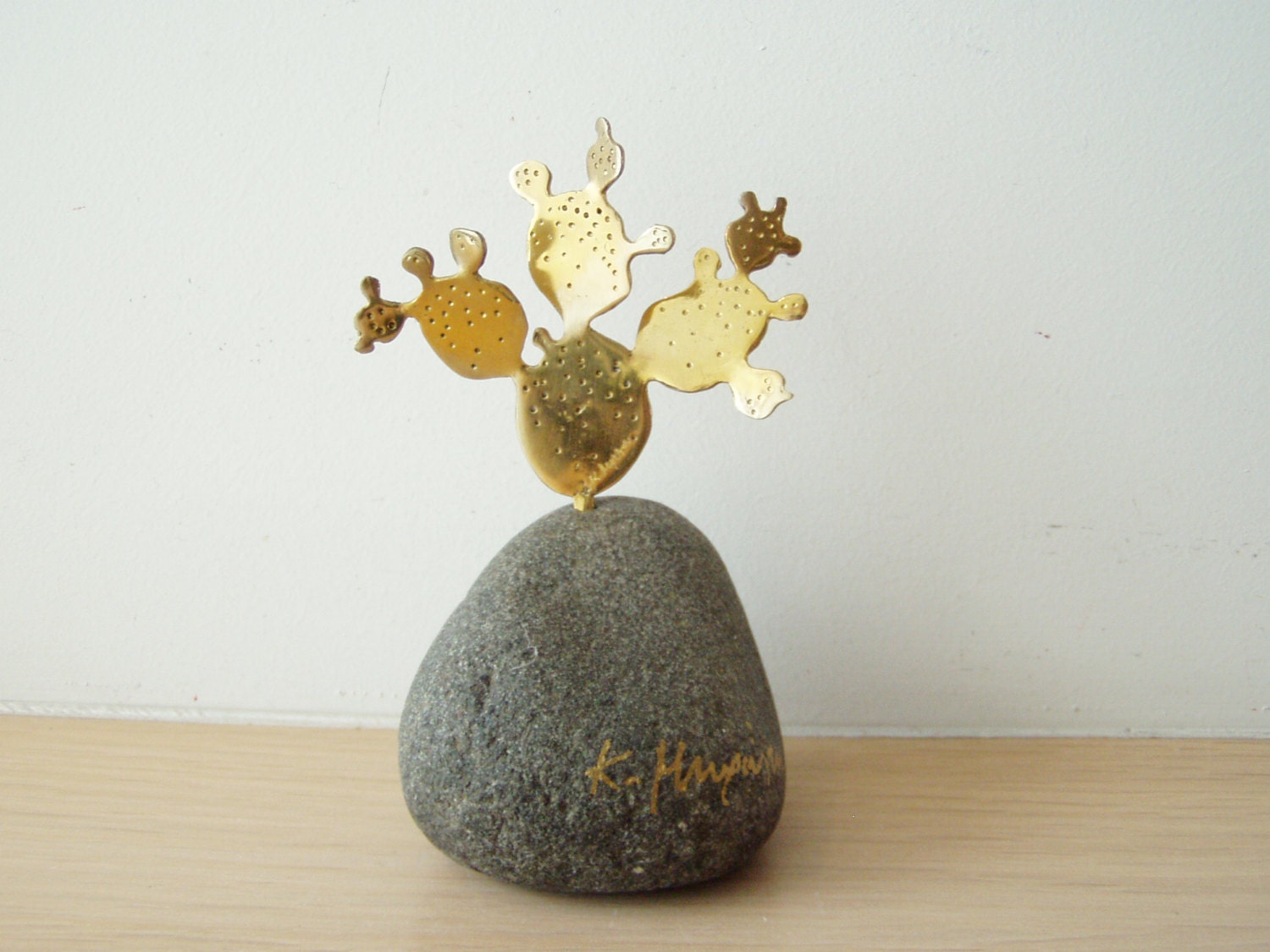 Brass cactus sculpture, opuntia cactus sculpture on grey stone, prickly