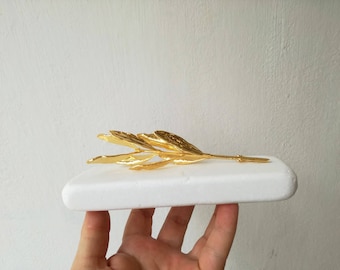 Gold olive branch on white marble, olive twig on white stone, Greek olive gift in gold