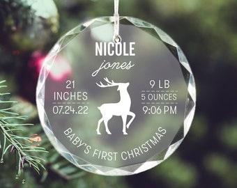 May include: Clear, faceted glass Christmas ornament with white text and a deer silhouette. The ornament includes the name "Nicole Jones", birth measurements of 21 inches and 9 pounds 5 ounces, and the phrase "Baby's First Christmas".