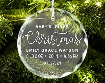 May include: Clear, faceted Christmas ornament with the text "BABY'S FIRST Christmas" and baby's birth details: Emily Grace Watson, 8 lb 2 oz, 20 inches, and 4:56 PM on 07.27.21. The ornament hangs from a white string.