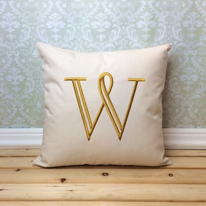 May include: A white pillow with a gold embroidered letter "W" in a decorative font.