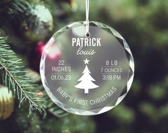 May include: Clear glass Christmas ornament with a white silhouette of a Christmas tree and the text "Patrick louis", "22 inches", "01.06.23", "8 lb", "7 ounces", "3:18 PM", and "Baby's First Christmas".