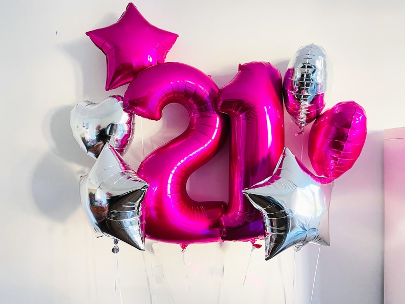May include: A pink number 21 balloon bouquet with silver star and heart balloons.
