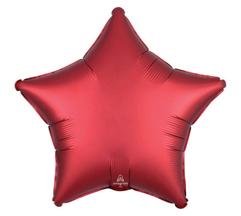 May include: A large, red star-shaped balloon with a matte finish. The balloon has five points and is inflated. The brand name "Anagram" is printed on the balloon.