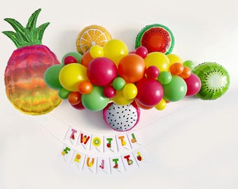 May include: A colorful fruit-themed balloon arch with a banner that reads "Two-tted Fruit-t", perfect for a birthday party or celebration.