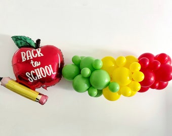 May include: A colourful back-to-school balloon display. It includes a red apple-shaped balloon with the text "BACK to SCHOOL", a yellow pencil balloon, and a garland of green, yellow, and red balloons. Ideal for classroom decorations.