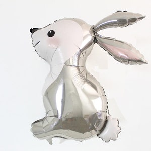 May include: A silver foil balloon shaped like a rabbit. The balloon has a white face with black eyes and a pink nose.