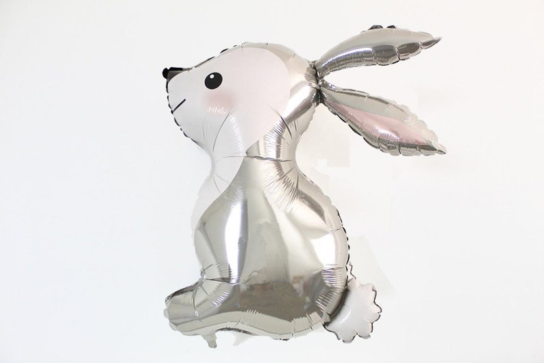 May include: A silver foil balloon shaped like a rabbit. The balloon has a white face with black eyes and a pink nose.