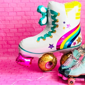 May include: A white and blue roller skate balloon with a rainbow and stars design. The balloon is next to a pair of blue roller skates with gold wheels.