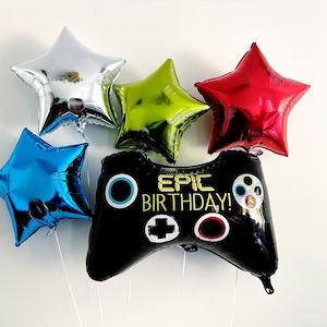 May include: A black and white video game controller balloon with the text "EPIC BIRTHDAY!" in gold letters. The controller balloon is surrounded by five star-shaped balloons in silver, red, green, and blue.