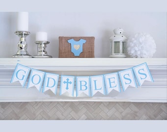 Puede incluir: Una pancarta azul y blanca con las palabras "God Bless" en letras blancas. La pancarta está decorada con una pequeña cruz blanca y un borde blanco cosido.