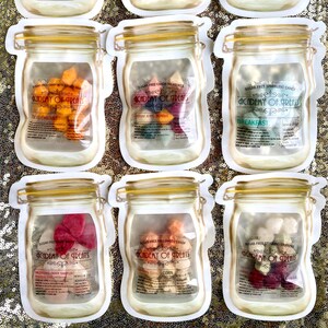May include: Nine clear glass jars with white lids, each containing different types of sugar-free candy. The jars are labeled with the text "Academy of Treats" and the names of the different candy flavors, such as "Calming Crystals", "Keto Candy", and "Matcha Mint".