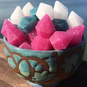 May include: A bowl filled with colorful sugar crystals in the shapes of diamonds. The bowl is a light blue color with a brown and white pattern.