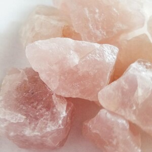 Pode incluir: Uma coleção de cristais de quartzo rosa, mostrando as variações naturais na cor e textura da pedra.