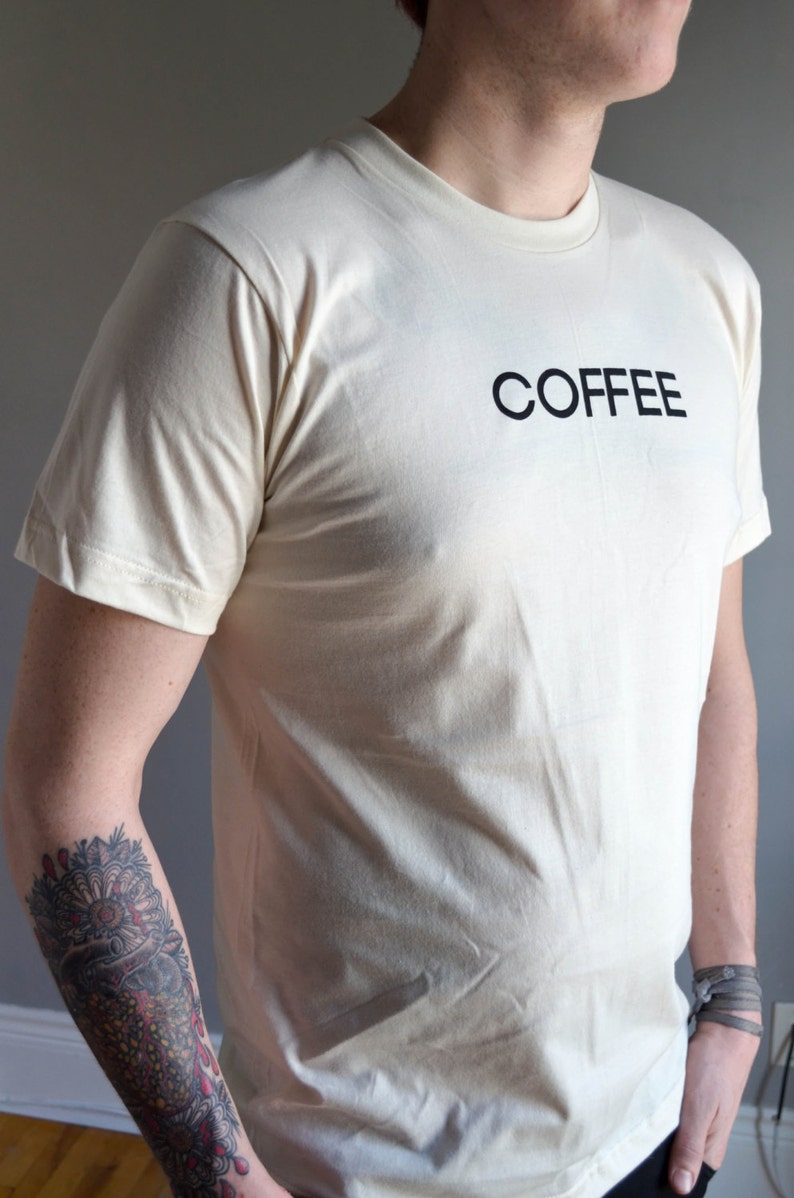 Light coloured, short sleeve t-shirt screen printed to say Coffee in dark font.