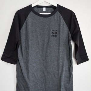 Raglan half length sleeve t-shirt in dark colours, screen printed to say Team No Fun in small type, in size large.