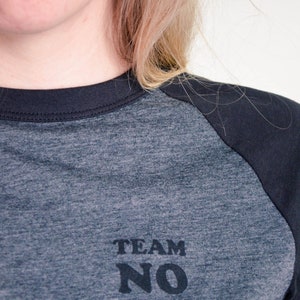 Close up of t-shirt in dark colours, screen printed to say Team No Fun in small, dark coloured type.