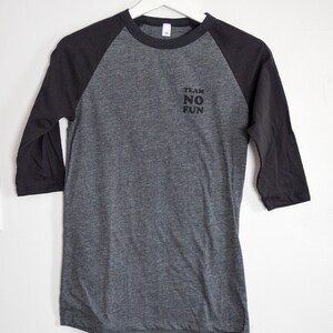 Raglan half length sleeve t-shirt in dark colours, screen printed to say Team No Fun in small type, in size extra small.