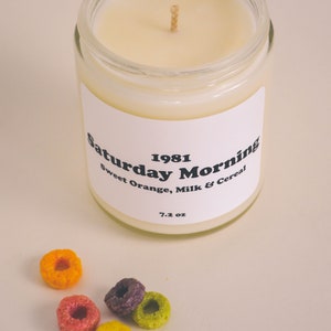 Large container candle in clear glass jar with metal lid, shown with Froot Loops cereal pieces.