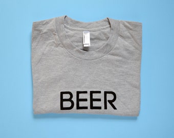 Op de afbeelding: Een grijs T-shirt met het woord "BEER" in zwart op de voorkant.