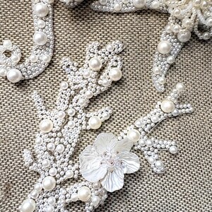 Close up view of a handmade white pearl starfish applique with intricate central beadwork.