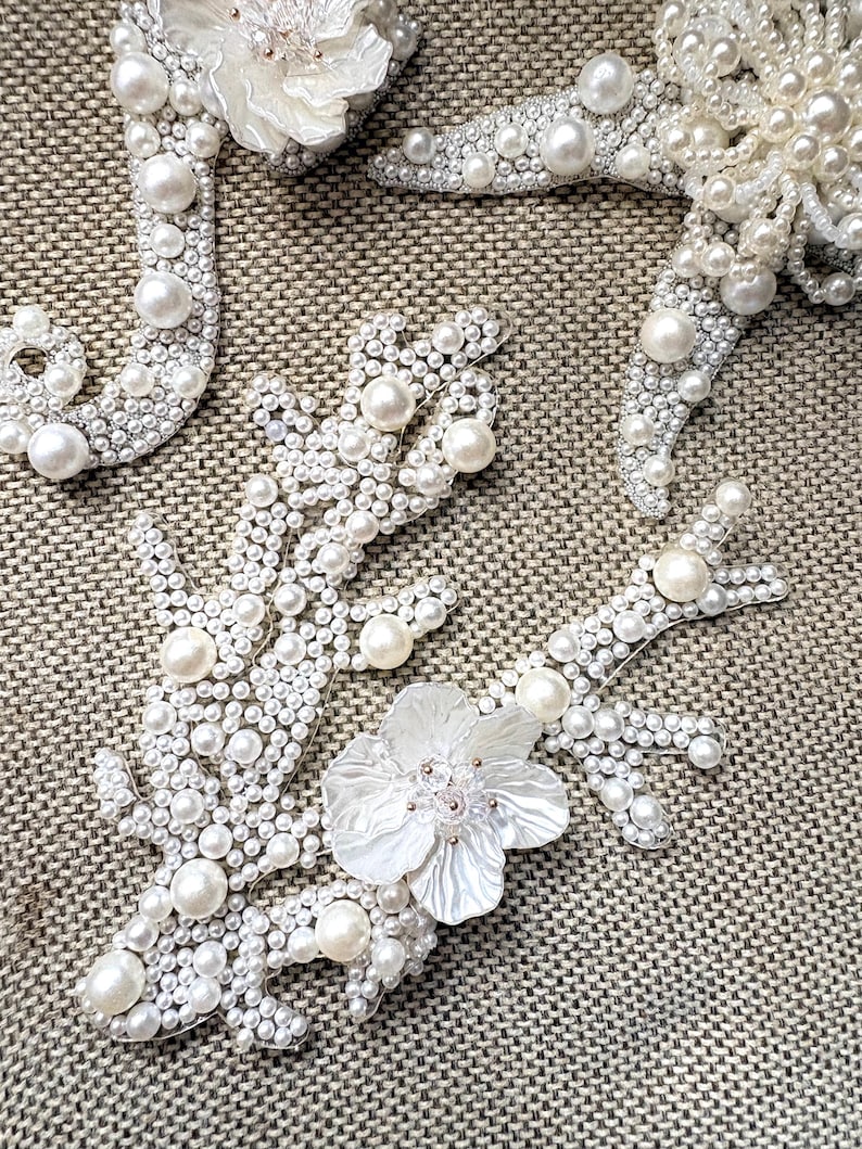Close up view of a handmade white pearl starfish applique with intricate central beadwork.