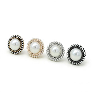 Puede incluir: Cuatro pendientes de perlas con diferentes acabados metálicos. Cada pendiente presenta una perla blanca redonda grande rodeada por un borde de perlas más pequeñas y un marco metálico decorativo en tonos dorados, plateados y negros. Fondo blanco.