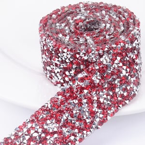 May include: A roll of red and silver rhinestone trim. The trim is made of small, faceted rhinestones that are arranged in a repeating pattern.