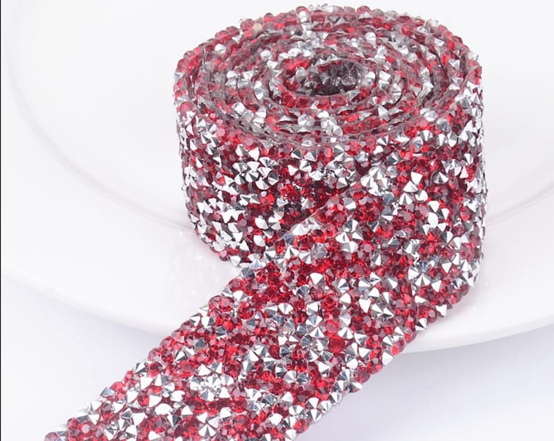 May include: A roll of red and silver rhinestone trim. The trim is made of small, faceted rhinestones that are arranged in a repeating pattern.