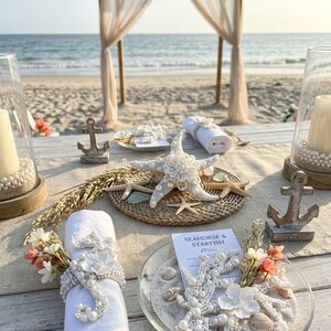 Beach wedding table setting featuring pearl seahorse napkin rings and starfish plate decor.