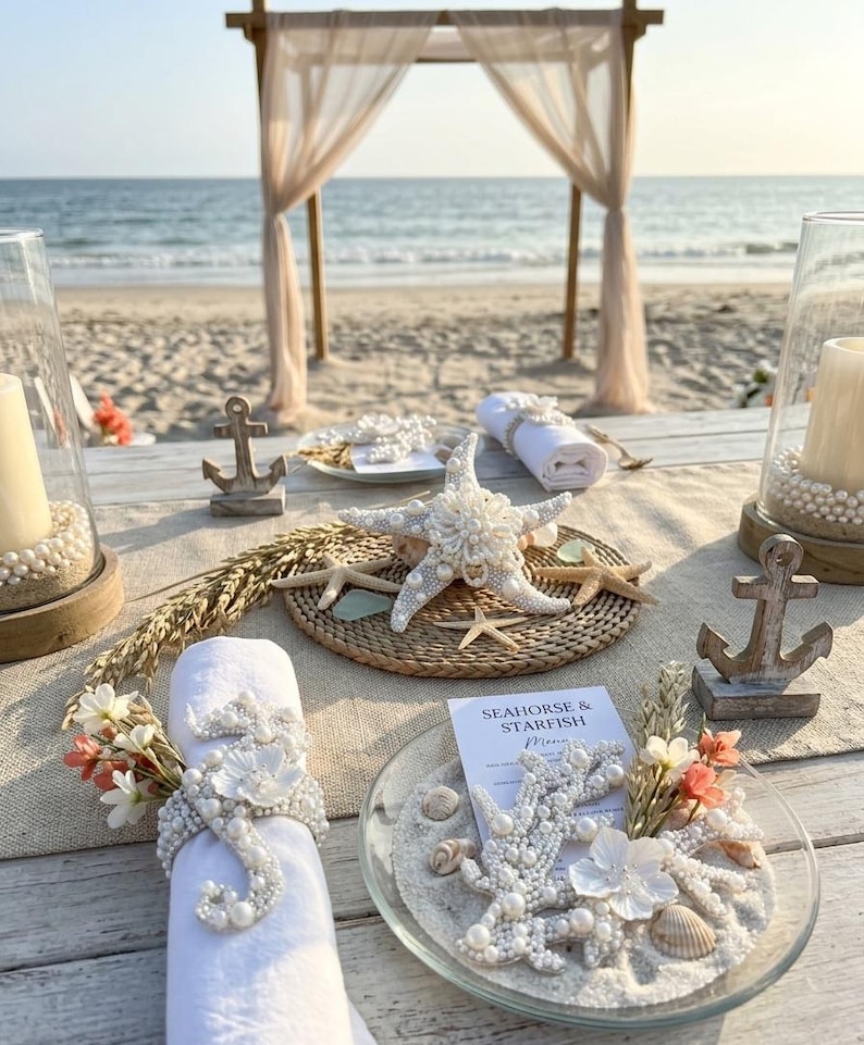Beach wedding table setting featuring pearl seahorse napkin rings and starfish plate decor.