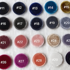 Puede incluir: Una colección de veinte círculos de tela de terciopelo en varios colores, cada uno con un número blanco del #11 al #30. Los colores incluyen tonos de azul, verde, rosa, morado y dorado. Los círculos están dispuestos en filas sobre una superficie blanca.