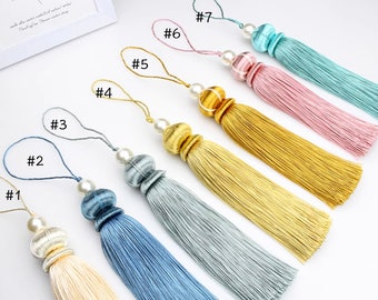 Puede incluir: Siete adornos de borla con cuentas de perla y borlas de diferentes colores. Las borlas son de los siguientes colores: beige, azul, azul claro, gris, dorado, rosa y azul claro.