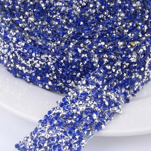 May include: A roll of blue and silver rhinestone trim. The trim is made of small, faceted rhinestones that are set in a clear adhesive backing.