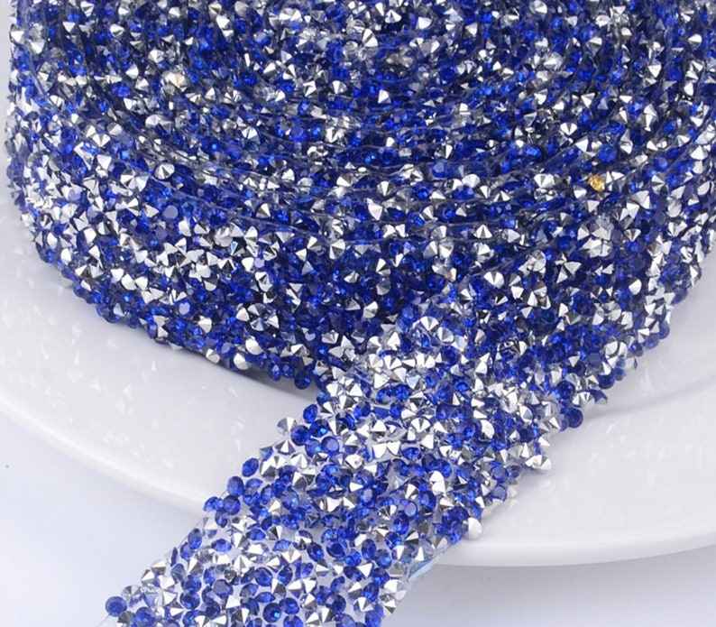 May include: A roll of blue and silver rhinestone trim. The trim is made of small, faceted rhinestones that are set in a clear adhesive backing.