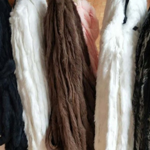 May include: Five different faux fur swatches hanging on a rack. The swatches are black, white, brown, white, and gray and black.