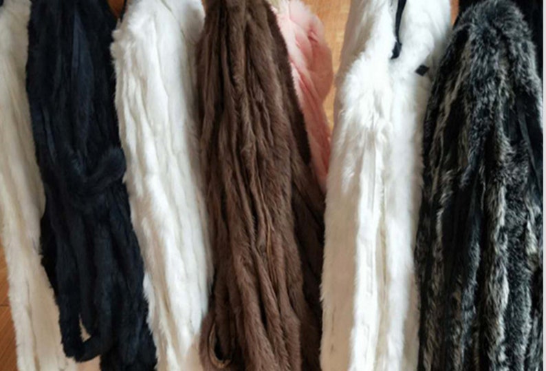 May include: Five different faux fur swatches hanging on a rack. The swatches are black, white, brown, white, and gray and black.