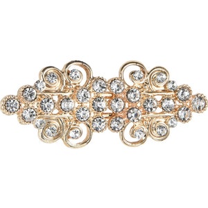 May include: A gold-toned hair clip with a decorative design featuring clear rhinestones.