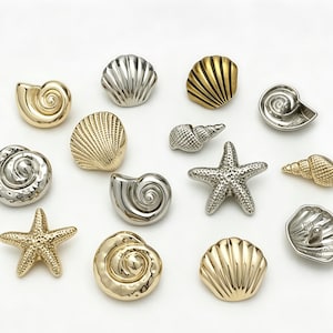 Pode incluir: Uma variedade de ornamentos decorativos de conchas e estrelas-do-mar em tons dourados e prateados. A coleção inclui várias formas de conchas e uma estrela-do-mar, todas com texturas detalhadas e um acabamento metálico.