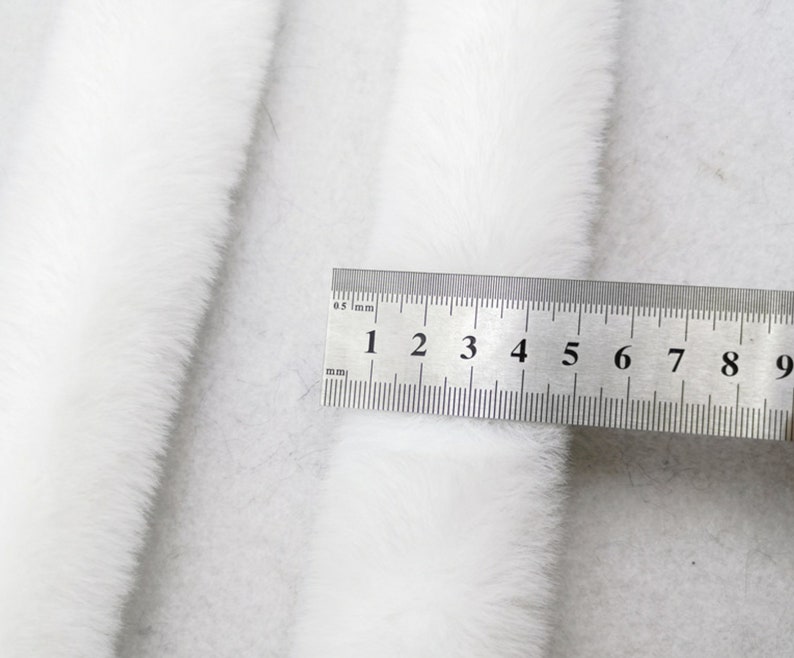 May include: White faux fur trim with a ruler measuring 9 centimetres in length.