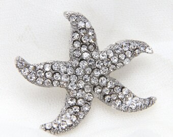 Op de afbeelding: Een zilveren zeester broche met heldere strass steentjes. De broche is een populair accessoire om elke outfit een vleugje glamour te geven.