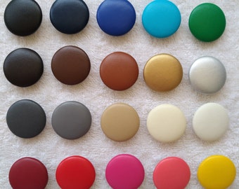Könnte beinhalten: Sortiment von 20 runden Knöpfen in verschiedenen Farben, darunter Schwarz, Blau, Braun, Gold, Grau, Grün, Beige, Elfenbein, Rosa, Rot, Silber und Gelb. Die Knöpfe sind aus einem glatten, strukturierten Material gefertigt.