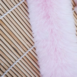 May include: A long, fluffy pink faux fur trim. The fur is soft and plush, and it would be perfect for adding a touch of luxury to any project.