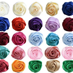 Könnte beinhalten: Eine Sammlung von Satinrosen in verschiedenen Farben, darunter Weiß, Gelb, Blau, Rot, Lila, Rosa und Grün. Die Rosen sind in Reihen angeordnet und zeigen ihr detailliertes Blütenblattdesign. Diese dekorativen Blumen eignen sich für Bastelarbeiten und Verzierungen.