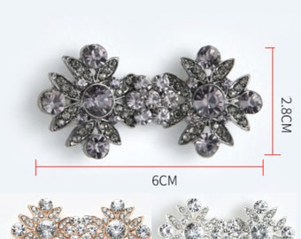 May include: Three silver-toned metal flower-shaped embellishments with clear and purple rhinestones. The embellishments are 6 inches wide and 2.8 inches tall.