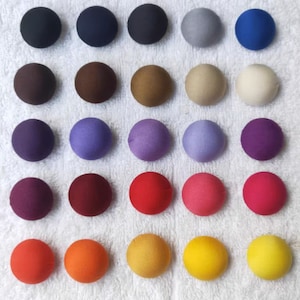 Könnte beinhalten: Sortiment von 30 runden Stoffknöpfen in verschiedenen Farben, darunter marineblau, braun, beige, lila, rot, orange und gelb.