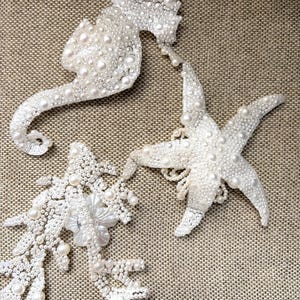 Close up view of a pearl seahorse applique featuring a delicate 3D white fabric flower.