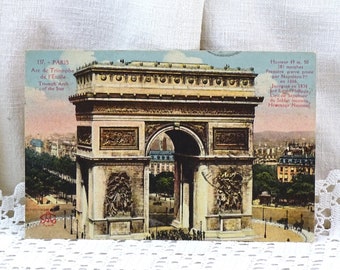 May include: A vintage postcard featuring a colorized image of the Arc de Triomphe in Paris, France. The postcard includes text in French and English, including the height of the monument, the number of steps, and the date it was inaugurated.