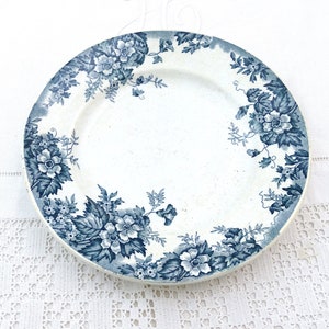 Puede incluir: Un plato de cerámica blanco con un diseño floral azul. El plato tiene un borde festoneado y un borde elevado.